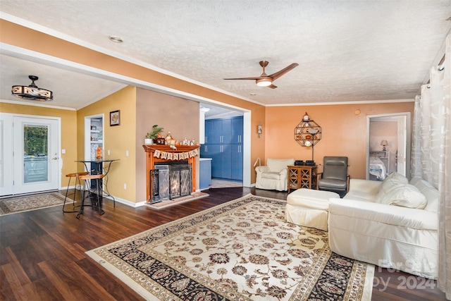 living room with ceiling fan, dark hardwood / wood-style floors, a textured ceiling, and ornamental molding