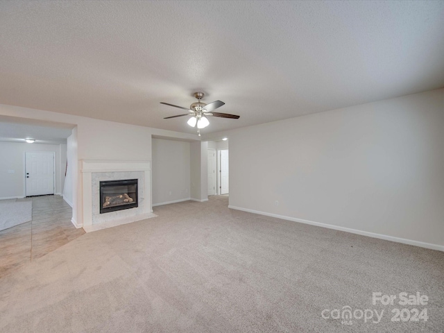 unfurnished living room with light carpet, a textured ceiling, ceiling fan, and a premium fireplace