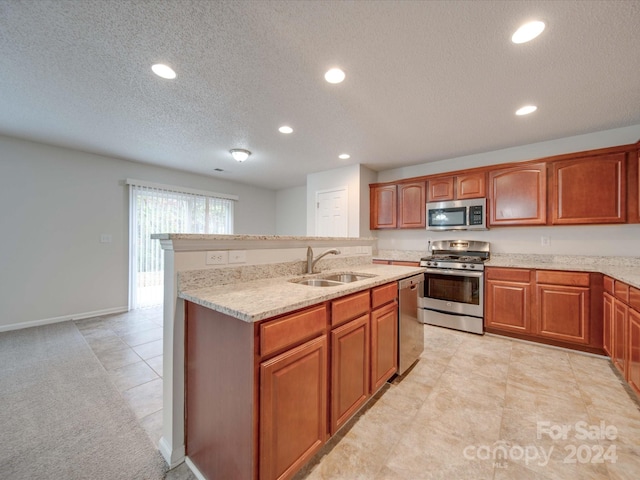 kitchen featuring a textured ceiling, light stone countertops, sink, and appliances with stainless steel finishes