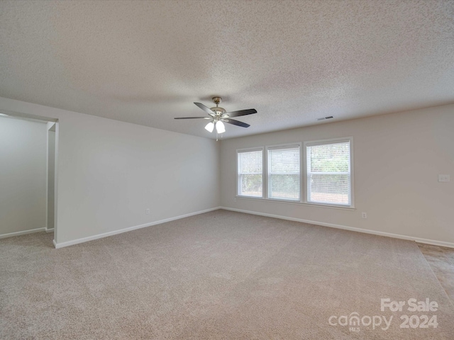 carpeted empty room with ceiling fan and a textured ceiling