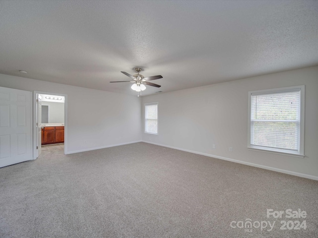 spare room featuring ceiling fan, a textured ceiling, and light carpet