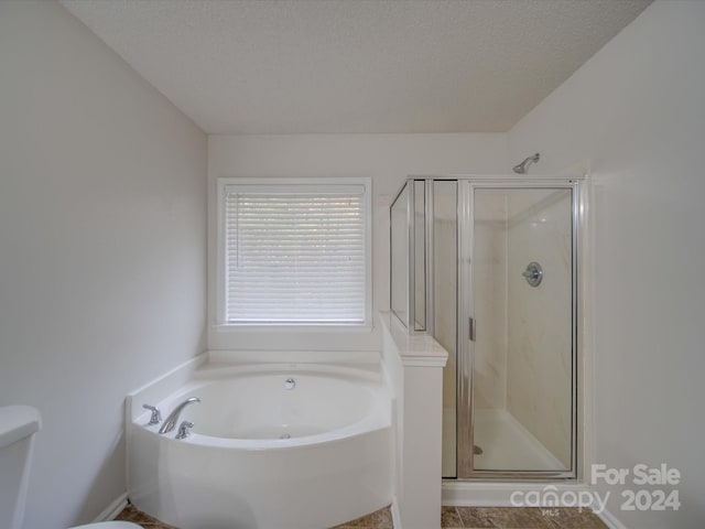 bathroom with plus walk in shower, a textured ceiling, and toilet