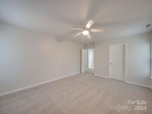 empty room with light carpet, ceiling fan, and a textured ceiling