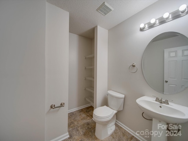 bathroom with a textured ceiling and toilet