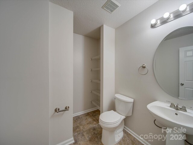 bathroom with sink, toilet, a textured ceiling, and tile patterned floors