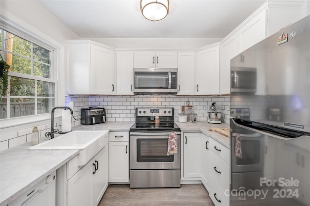 kitchen featuring white cabinetry, decorative backsplash, stainless steel appliances, and sink