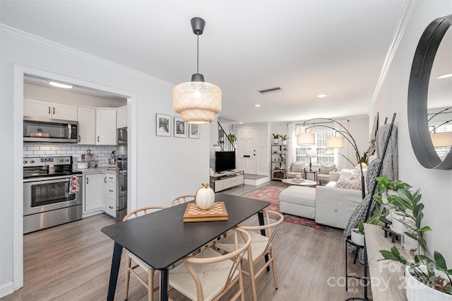 dining space with light hardwood / wood-style floors and crown molding