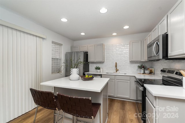 kitchen with hardwood / wood-style floors, appliances with stainless steel finishes, sink, and a center island