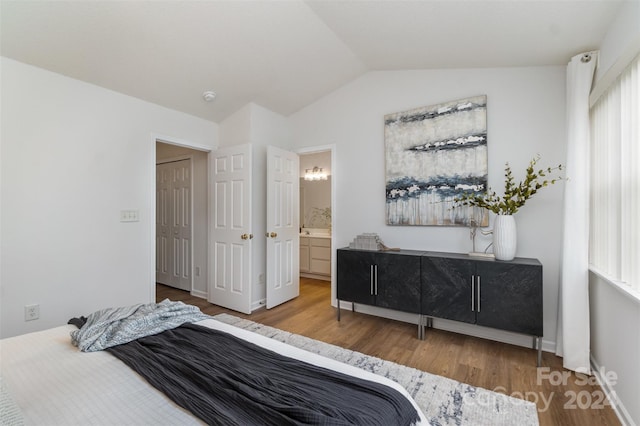 bedroom featuring lofted ceiling, wood-type flooring, and ensuite bathroom