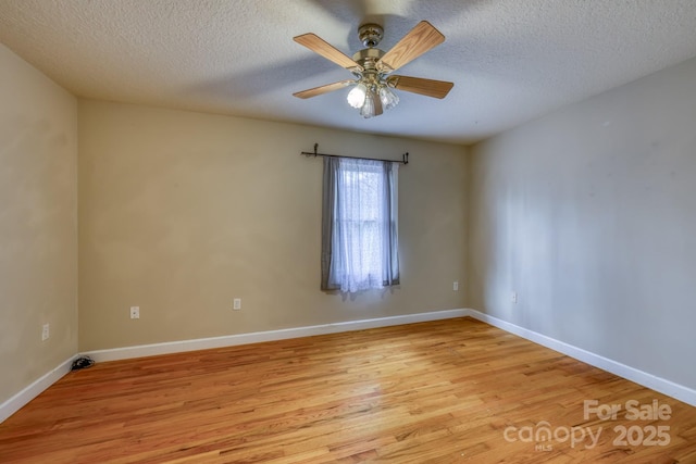 empty room with ceiling fan, light wood-type flooring, and a textured ceiling