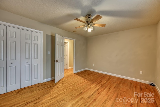 unfurnished bedroom featuring ceiling fan, a textured ceiling, and light hardwood / wood-style flooring