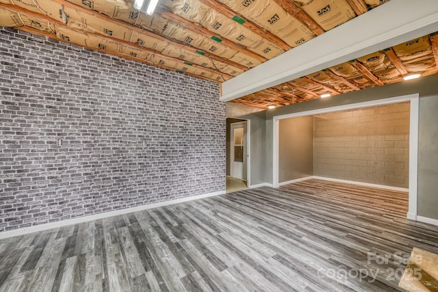 basement with brick wall and hardwood / wood-style floors