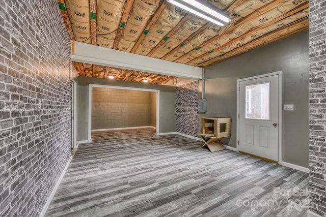 foyer with wood-type flooring and brick wall