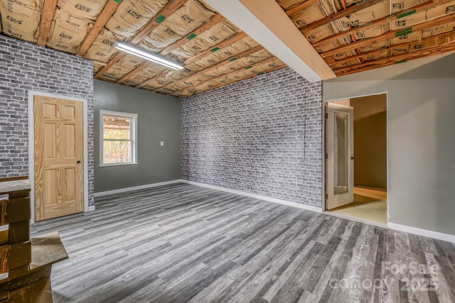 spare room with brick wall and hardwood / wood-style floors