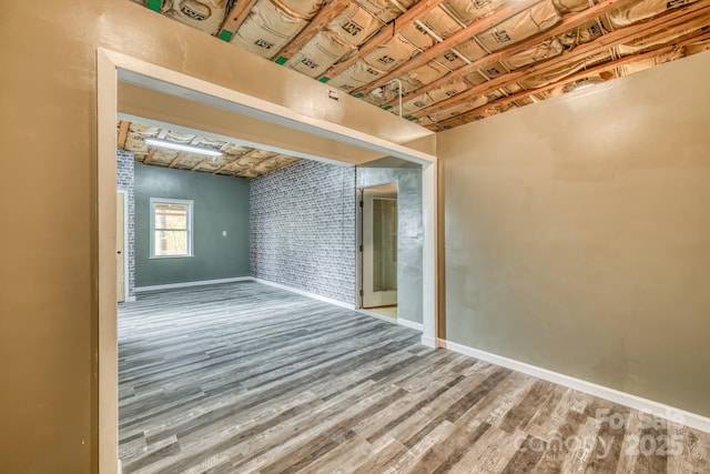 spare room with brick wall and hardwood / wood-style floors