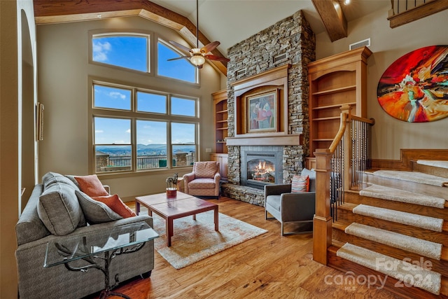 living room featuring ceiling fan, high vaulted ceiling, a mountain view, a fireplace, and light wood-type flooring