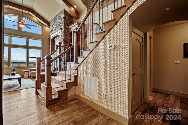 stairs with hardwood / wood-style floors, lofted ceiling with beams, and ceiling fan