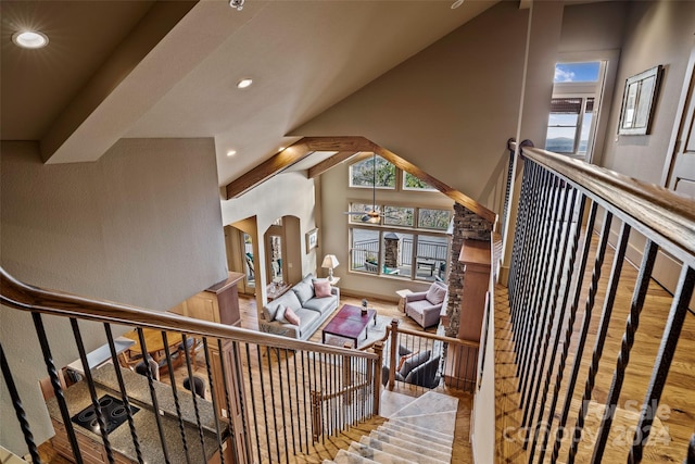 staircase featuring hardwood / wood-style floors, high vaulted ceiling, and an inviting chandelier