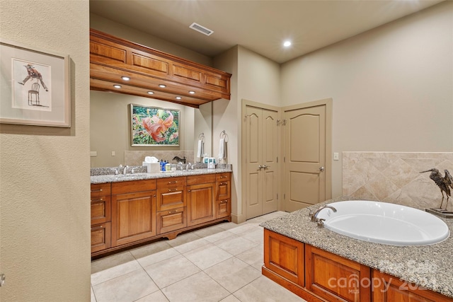 bathroom with tile patterned flooring, vanity, and a bath