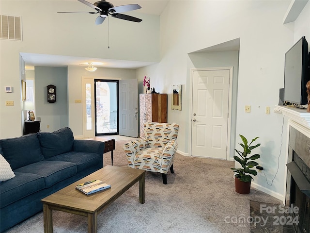 carpeted living room featuring ceiling fan and a high ceiling