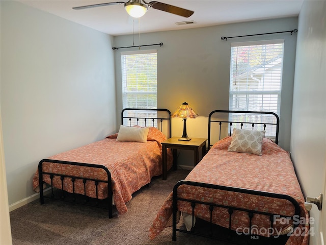 bedroom with ceiling fan, multiple windows, and dark carpet