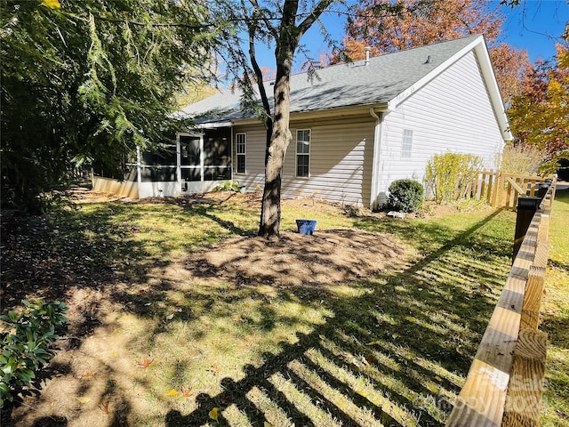 rear view of property featuring a lawn and a sunroom