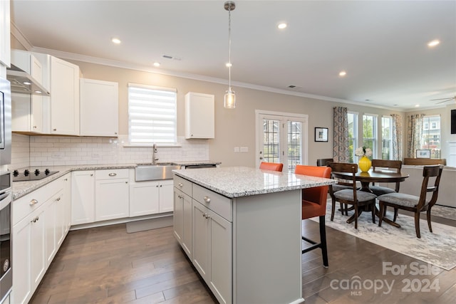 kitchen featuring hanging light fixtures, sink, a kitchen breakfast bar, white cabinets, and a center island