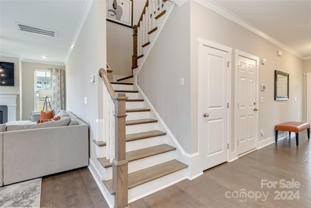 staircase with ornamental molding and hardwood / wood-style floors