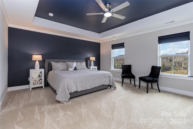 bedroom featuring ornamental molding, light carpet, ceiling fan, and a tray ceiling