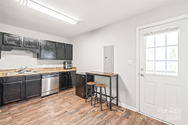 kitchen featuring a kitchen bar, stainless steel dishwasher, sink, light hardwood / wood-style flooring, and electric panel