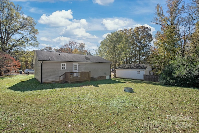 rear view of property with a shed, a deck, and a yard