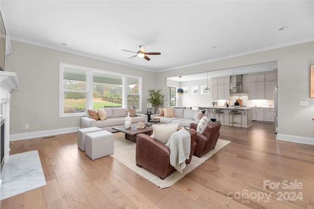 living room featuring ornamental molding, light hardwood / wood-style flooring, and ceiling fan