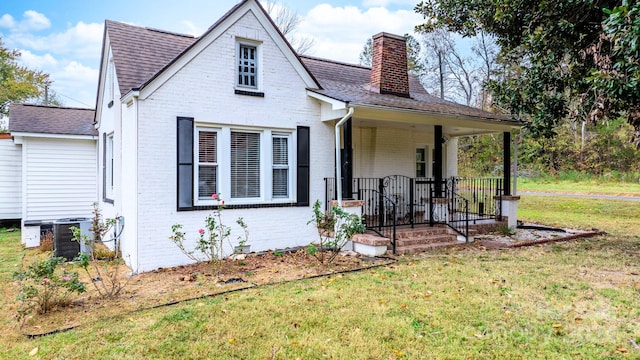 rear view of house with covered porch, central air condition unit, and a yard