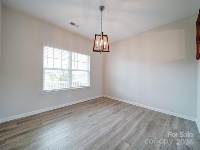 empty room featuring light hardwood / wood-style flooring and an inviting chandelier