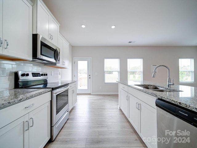 kitchen featuring white cabinets, stainless steel appliances, sink, and light stone counters