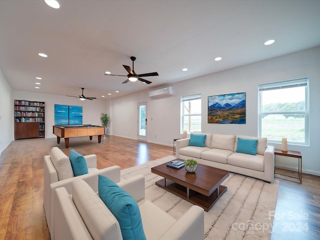 living room with an AC wall unit, pool table, a wealth of natural light, and light hardwood / wood-style floors