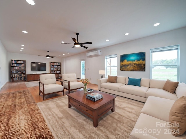 living room with ceiling fan, a wall mounted air conditioner, and light hardwood / wood-style floors