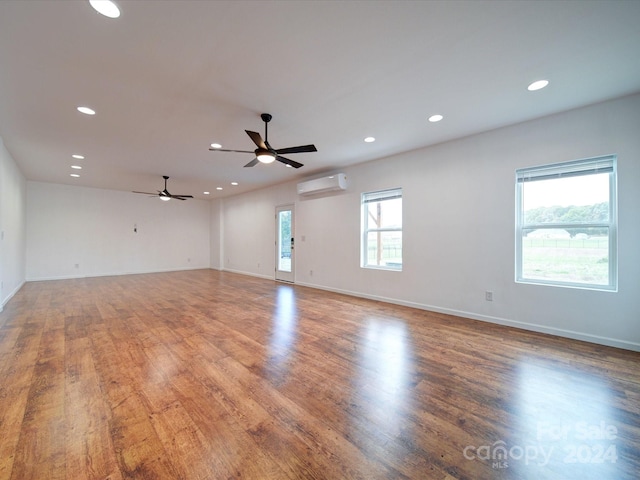 spare room featuring hardwood / wood-style floors, a wealth of natural light, and a wall mounted air conditioner