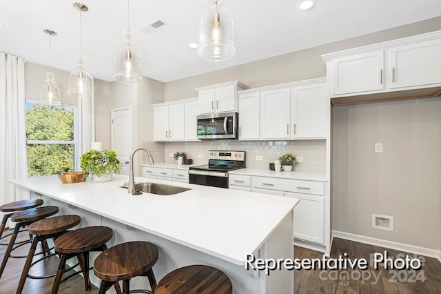 kitchen featuring a center island with sink, sink, pendant lighting, and appliances with stainless steel finishes