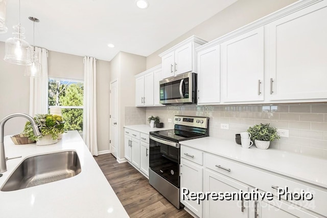 kitchen with stainless steel appliances, sink, dark hardwood / wood-style floors, white cabinets, and pendant lighting