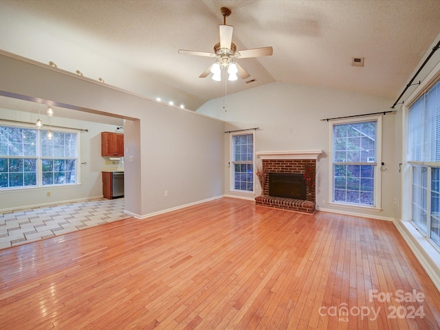 unfurnished living room with ceiling fan, light hardwood / wood-style flooring, lofted ceiling, and a brick fireplace