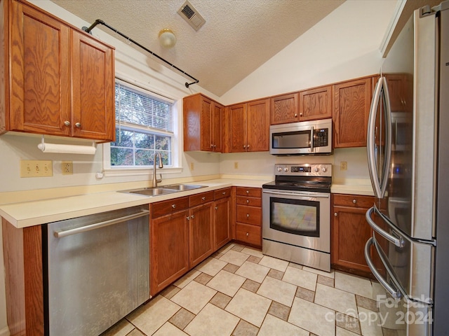 kitchen with sink, lofted ceiling, a textured ceiling, and appliances with stainless steel finishes