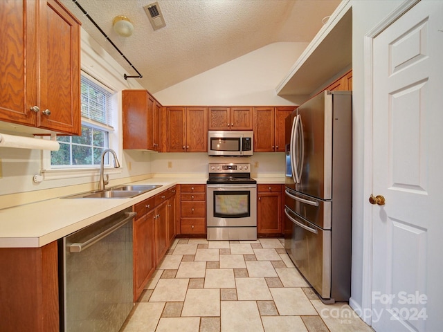 kitchen with a textured ceiling, stainless steel appliances, lofted ceiling, and sink