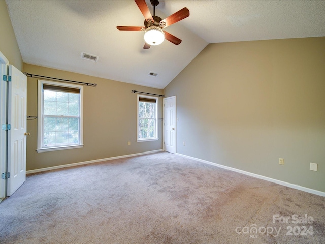 empty room featuring a textured ceiling, ceiling fan, lofted ceiling, and light carpet