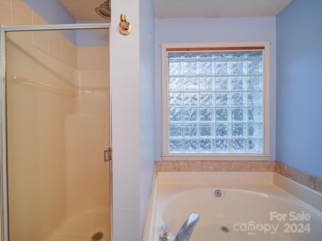 bathroom with a textured ceiling and separate shower and tub