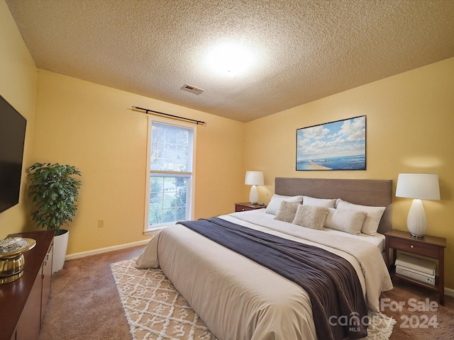 bedroom with light colored carpet and a textured ceiling