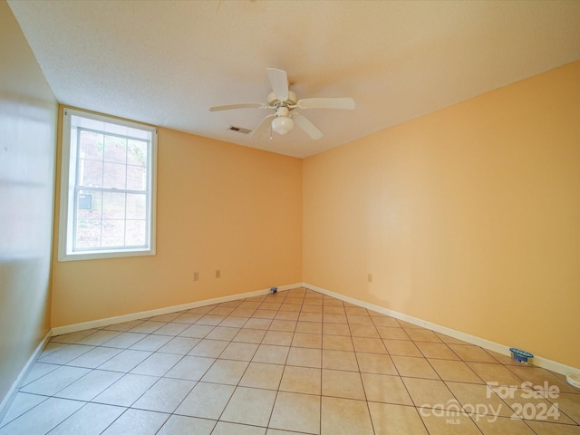 spare room with a textured ceiling, ceiling fan, and light tile patterned flooring