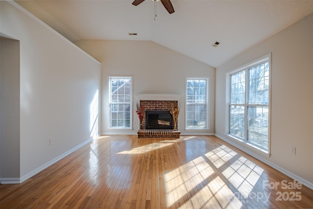 unfurnished living room with light wood-type flooring, lofted ceiling, a brick fireplace, and visible vents