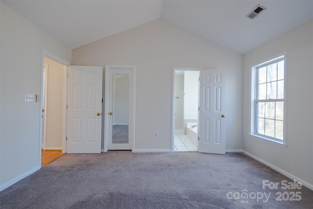 unfurnished bedroom with lofted ceiling, carpet, visible vents, and baseboards