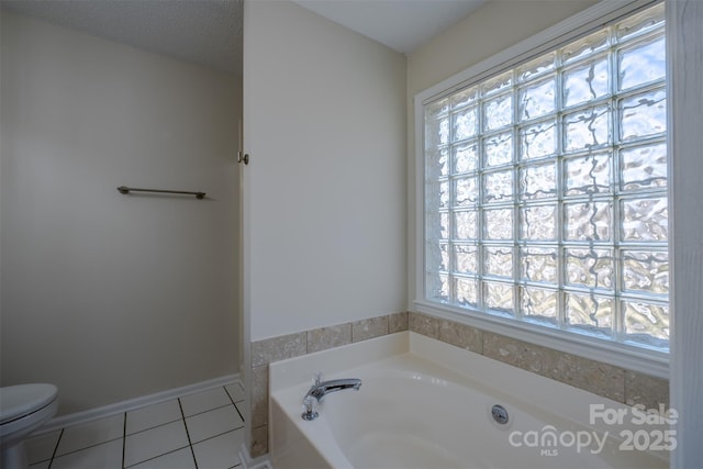 full bath featuring a garden tub, a healthy amount of sunlight, toilet, and tile patterned flooring